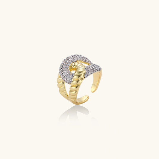Chunky gold-plated chain-link ring with curved segments and sparkling zirconia crystals on neutral background